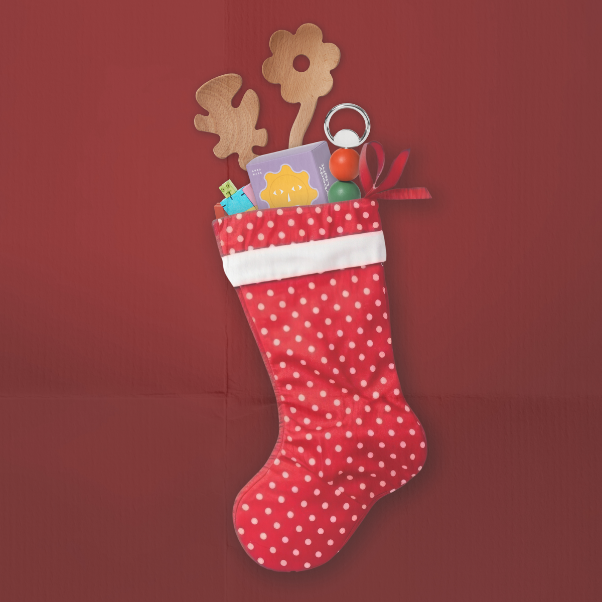 Red polka dot Christmas stocking with toys on a red background